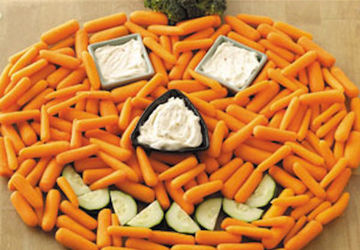 a plate of raw veggies arranged to resemble a jack-o-lantern